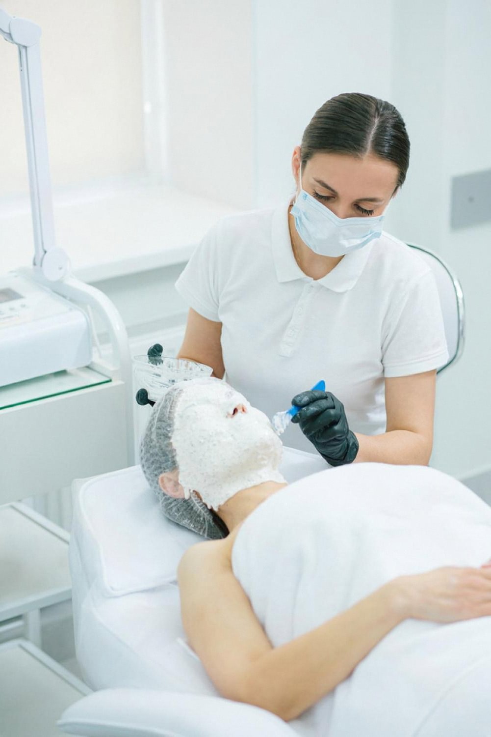 Dermatologist applying a treatment mask to a patient during a skin care session in a UAE clinic