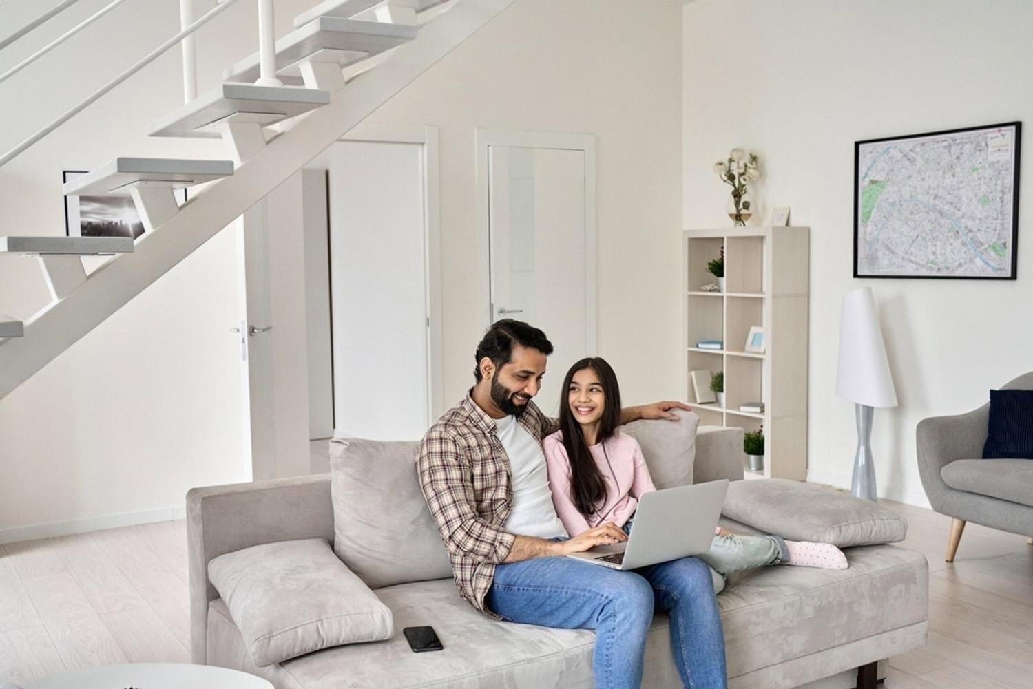 Father and daughter learning together on a laptop at home in the UAE