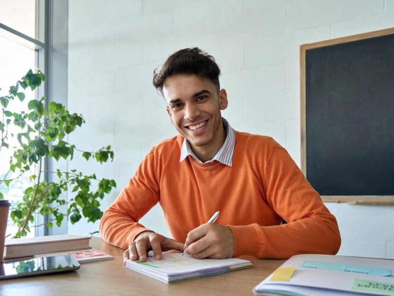 Smiling medical trainee reviewing ECG notes at a study desk