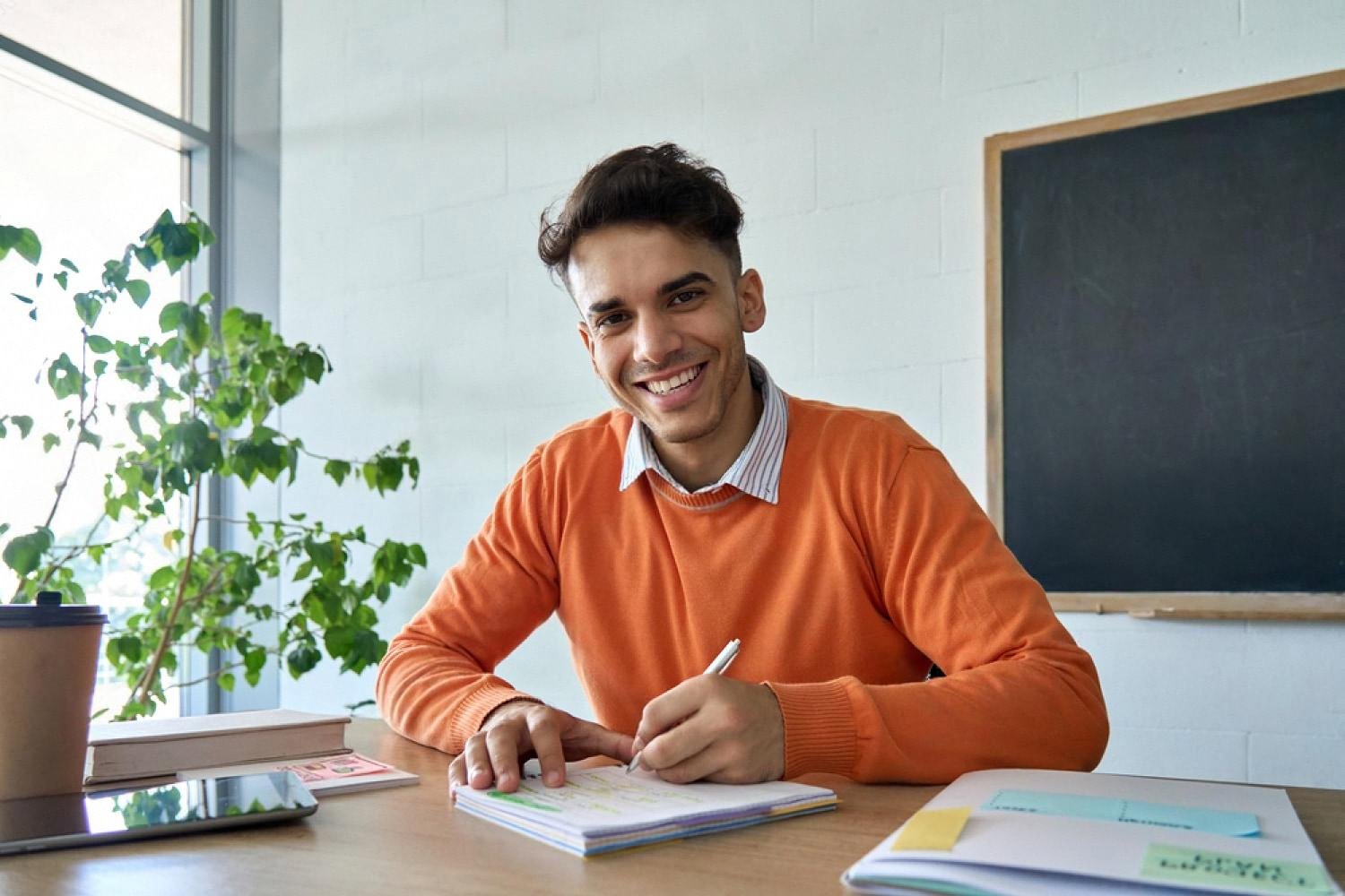 Smiling medical trainee reviewing ECG notes at a study desk